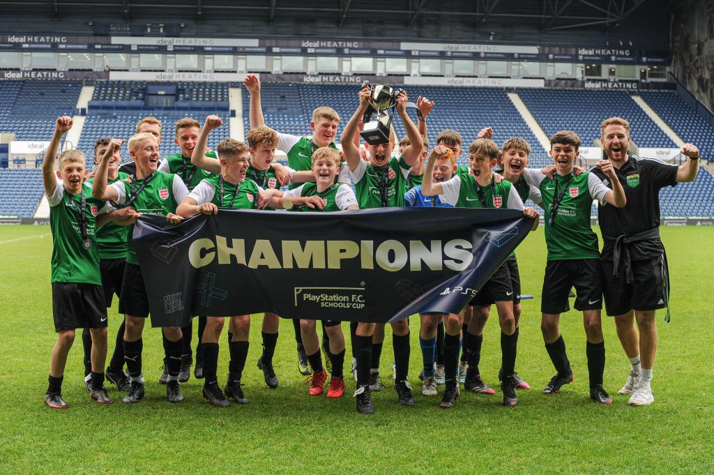 A winning team lifting the trophy and holding the winners' banner after becoming National Champions at West Bromwich Albion FC