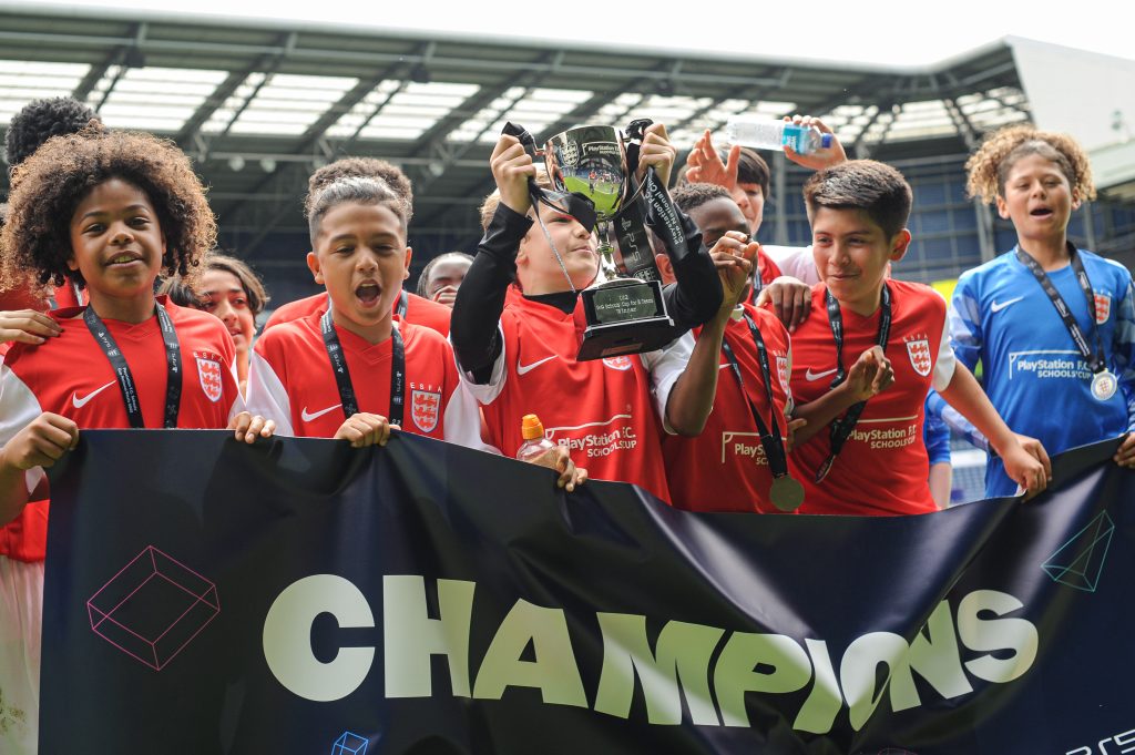 A team of PlayStation F.C. Schools' Cup National Champions, lifting the trophy