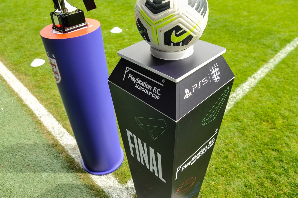 Two plinths displaying the match ball and winners' trophy on the pitch at West Bromwich Albion FC