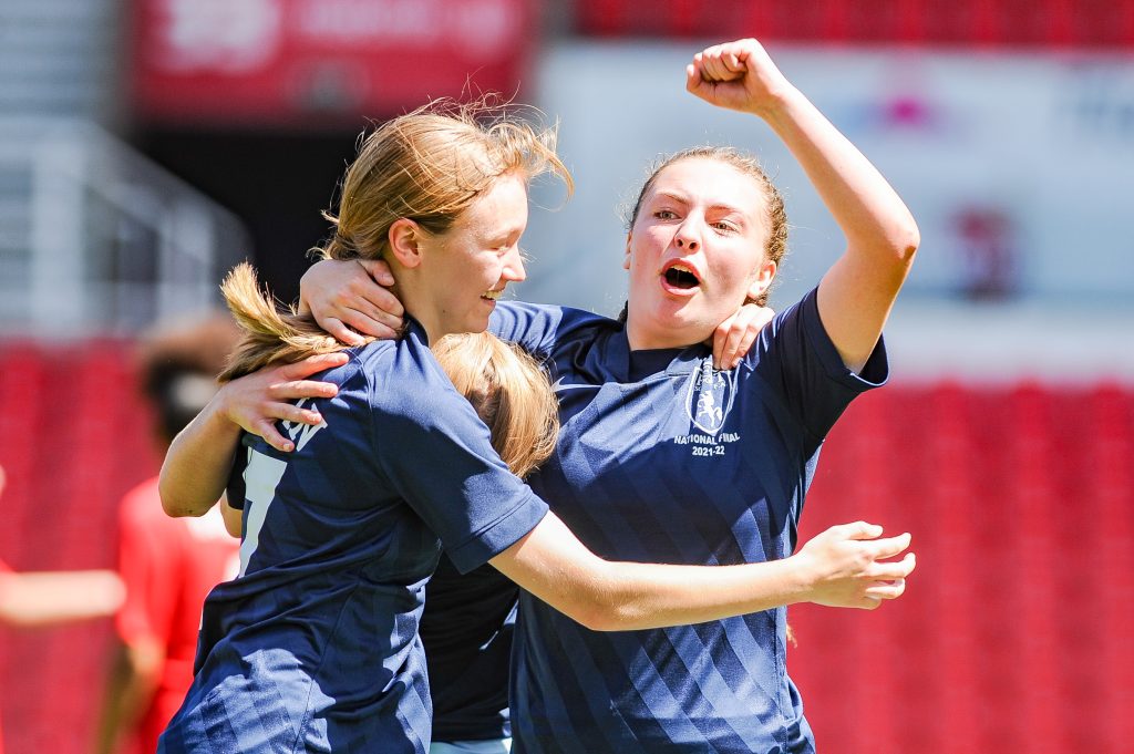 Two girls celebrating on the pitch during a national final match