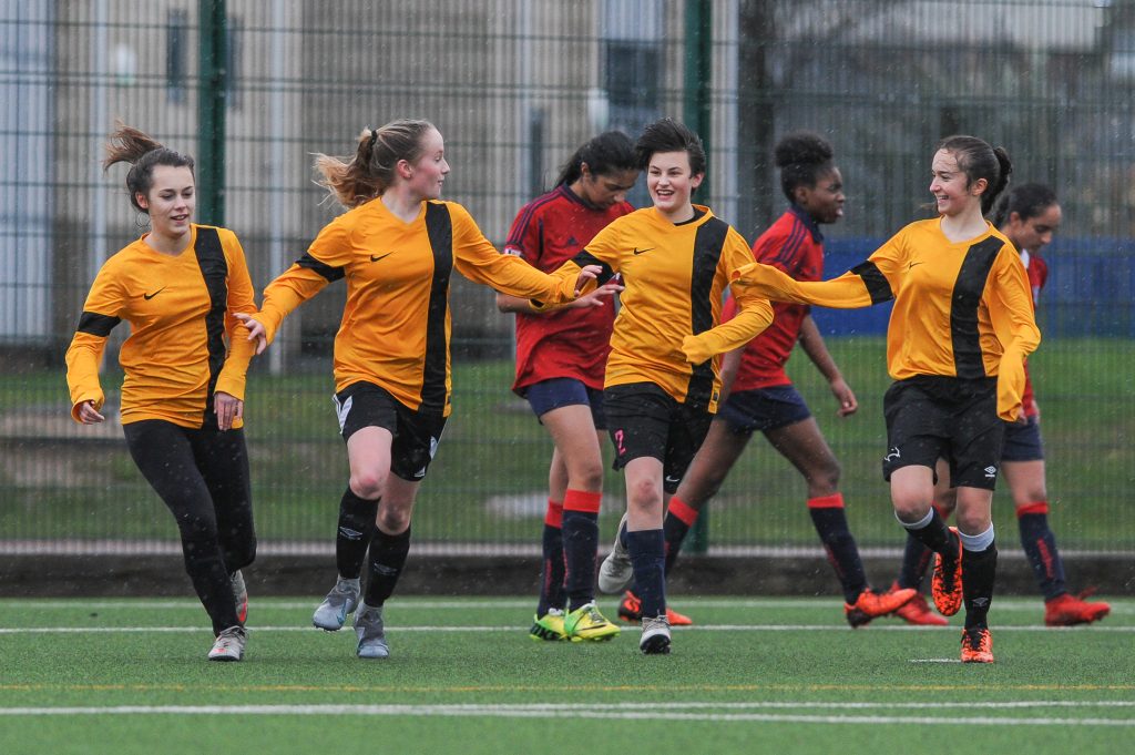 A girls' football team celebrating a goal